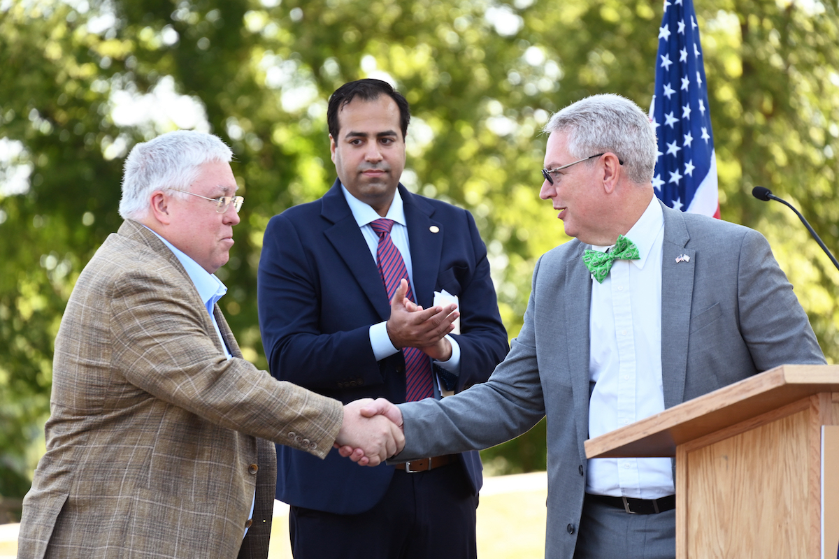 At a press conference, Rumbaugh (right) shakes hands with Governor Patrick Morrisey (left) in front of Shaz Umer, Director of Strategic Initiatives for USDOT.