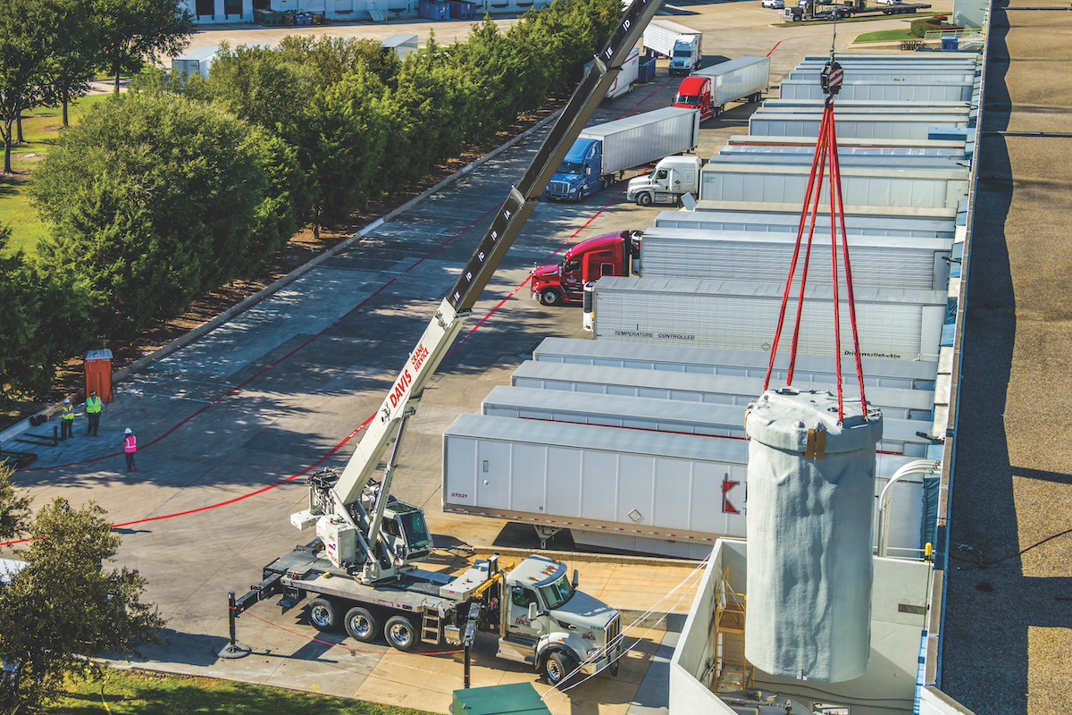 A Davis Crane Group operator lifts a tank part with a National Crane NBT60XL Boom Truck on a job site in the Dallas-Fort Worth area.