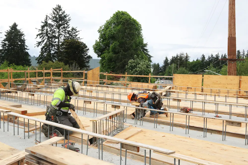 Rebar and wood planks are placed by two crew members to form the superstructure of the bridge deck for the future SR 509 bridge that will span over Des Moines Memorial Drive.