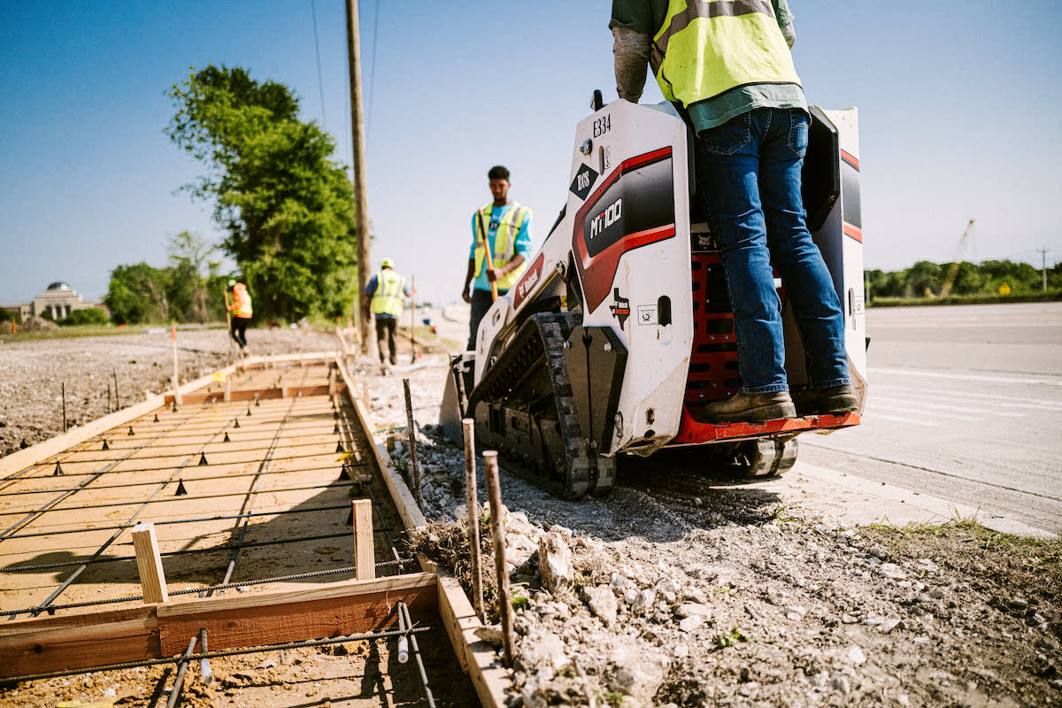 The crew prepares a job site using hand tools and a Bobcat MT100 Mini Track Loader.
