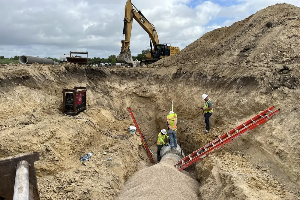 The crew installs 36-inch concrete steel cylinder pipe by open cut.