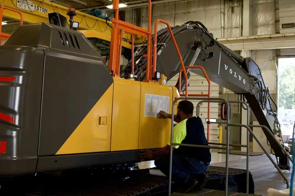 A Volvo CE employee adds a product sticker to an EC230 excavator on the production line at the Shippensburg facility.