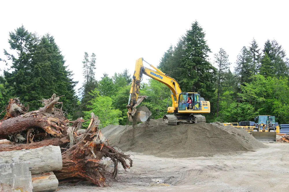 A crew member operates a Komatsu crawler excavator to move and haul earthwork.
