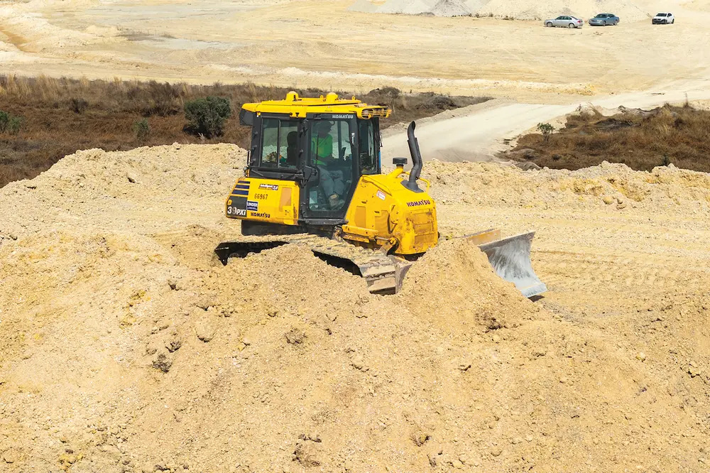 An operator cuts down piles and reaches grade around the job site with a Komatsu D39PXi IMC Dozer.