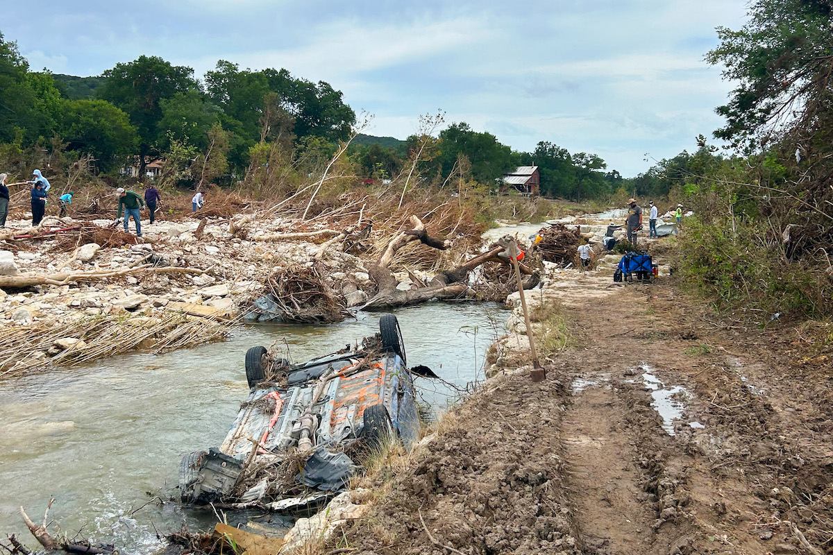 Debris and a submerged vehicle remain along the riverbank after flooding occurred in Kerr County.
