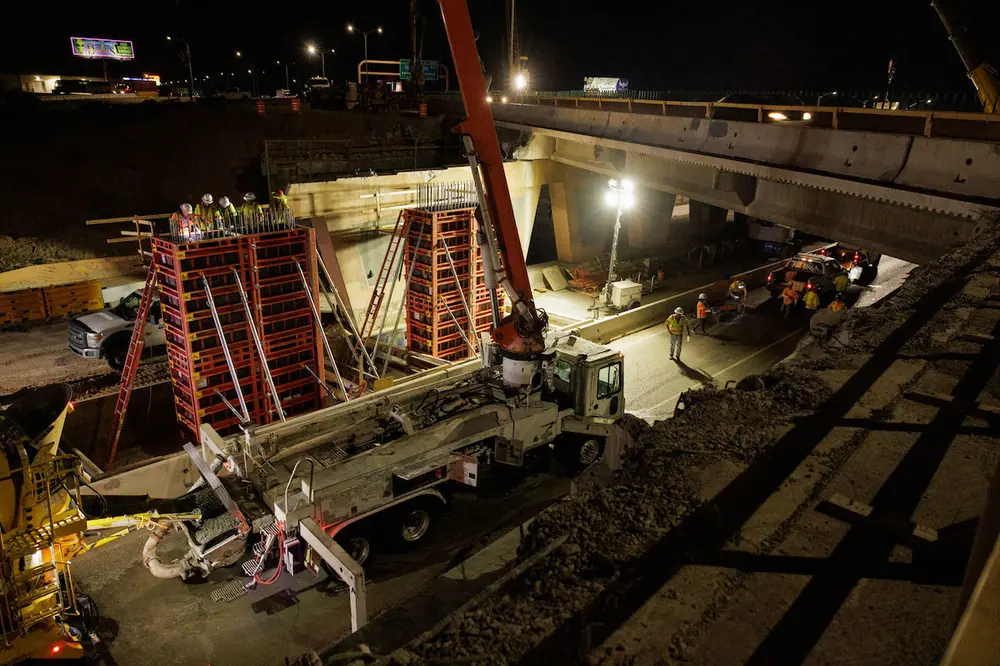 East of I-25 on Comanche Road, a pump truck is in place to bring concrete to the top of the bridge pier forms. Crews closed Comanche Road for the night work, for the safety of the traveling public.