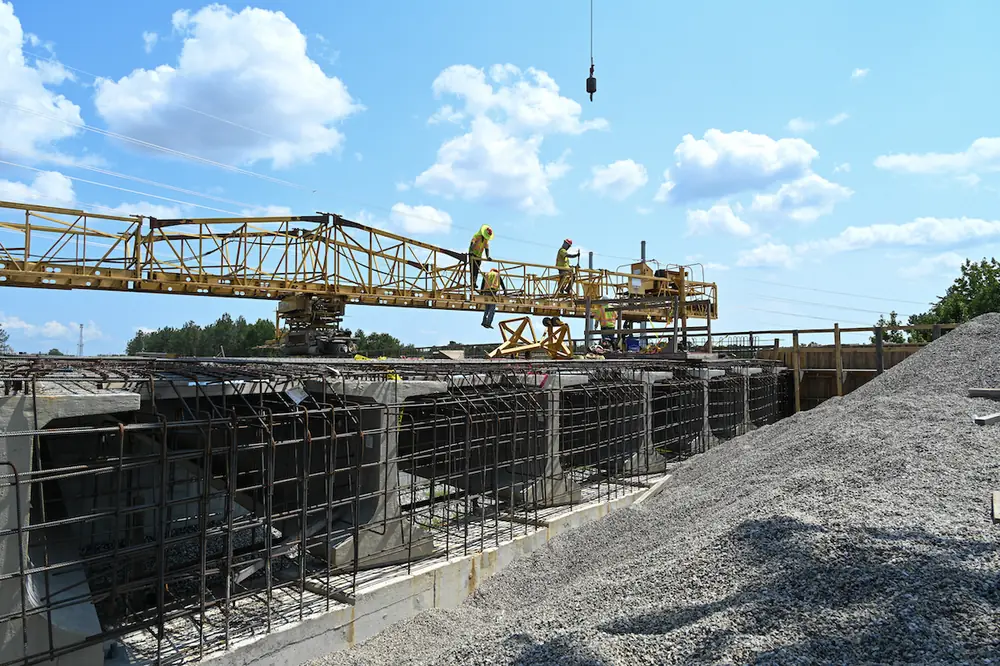 On the I-77 Exit 26 overpass bridge, contractors work to assemble a screed across the rebar framework.