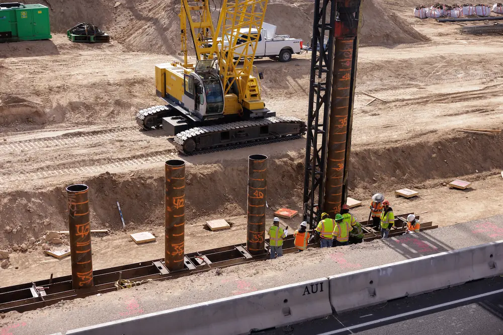 Piles are driven in the ground to support the base of the new bridge piers for the Montgomery Boulevard overpass above I-25.