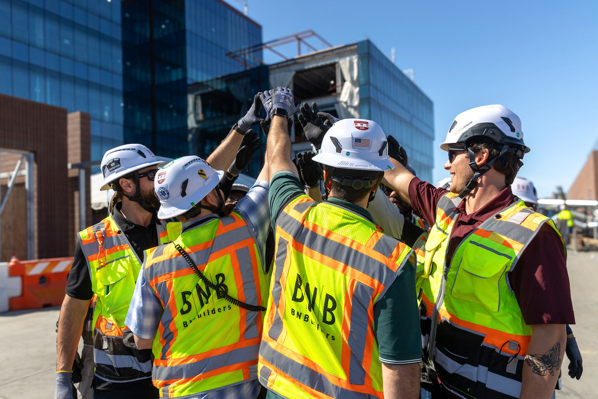 A group of construction workers high-five on the job site.