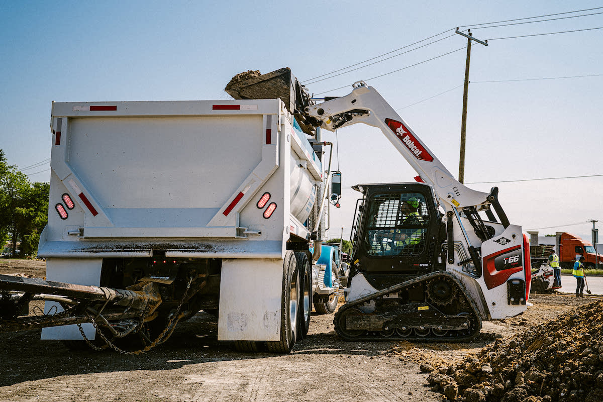 A bucket of material is dumped into a truck using a Bobcat T66 Compact Track Loader.