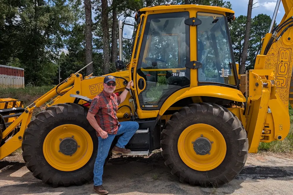 Koon poses with JCB’s commemorative one-millionth backhoe loader.