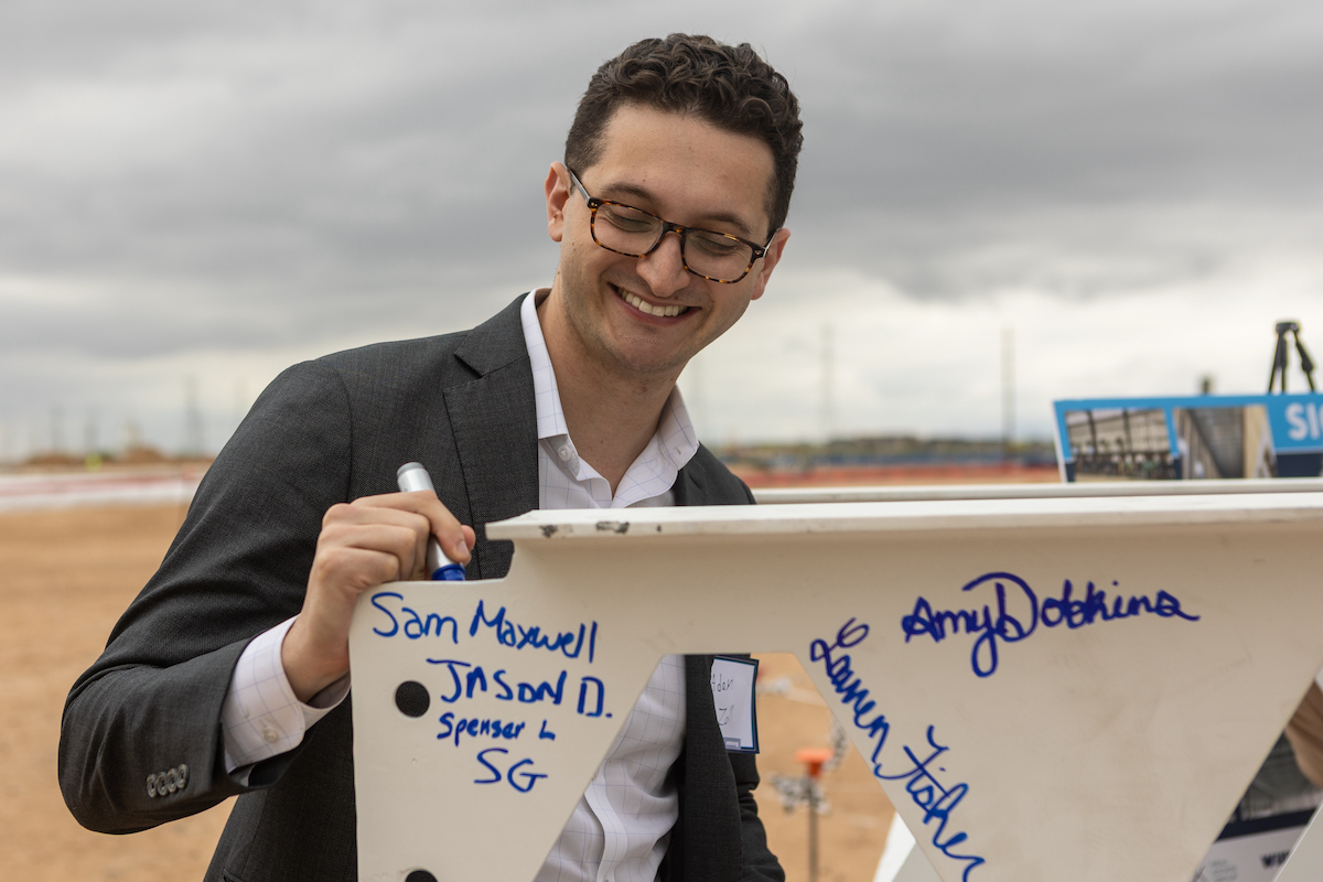 Mack Real Estate Group Vice President Adam Zall signs a steel beam that will be installed in the first building to go vertical.