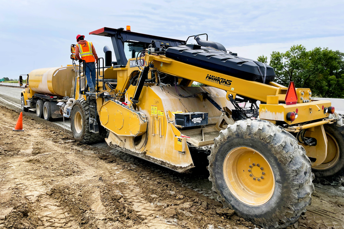 A soil stabilizer mixes cement and water with the subgrade soil.