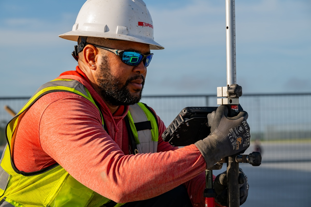 Paving Foreman Orestes Reyes operates survey equipment on Superior Construction’s Cecil Airport Expansion Apron job site in Jacksonville, Florida, to collect real-time data that feeds directly into project systems.